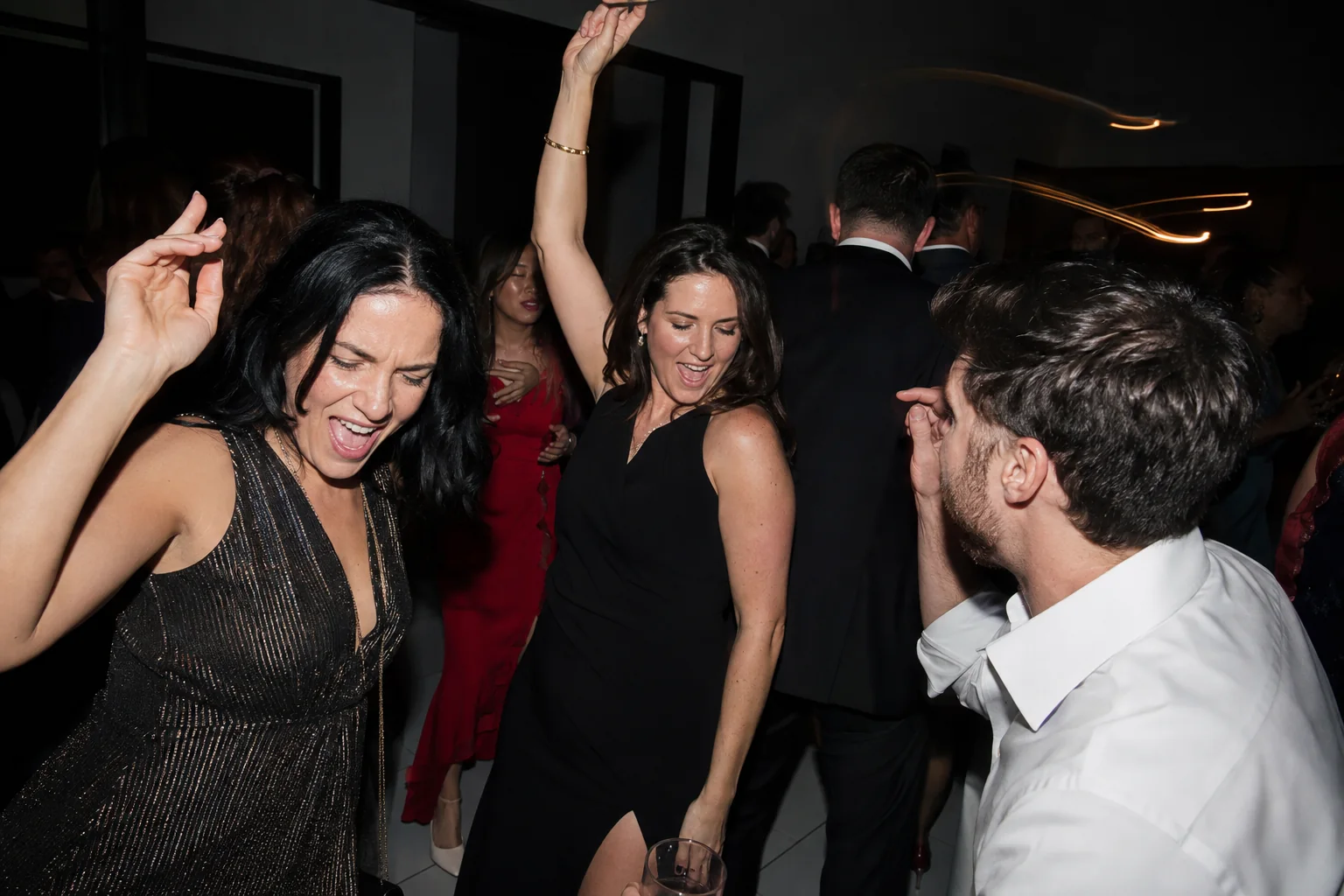 Wedding guests dancing together under direct flash